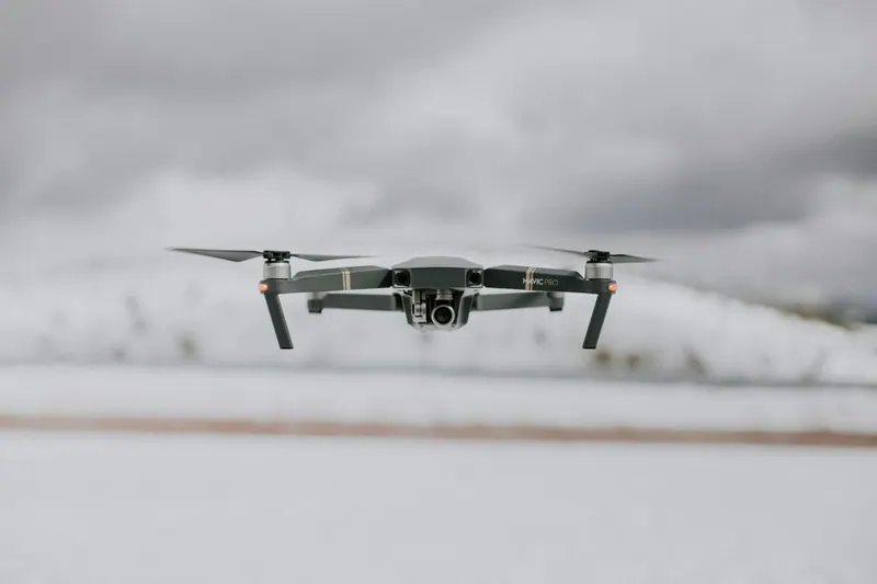 Quadcopter drone hovering over a snowy landscape, aerial drone videography