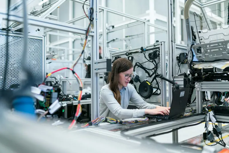 Engineer working on a laptop beside robotics equipment in a laboratory, industrial photography