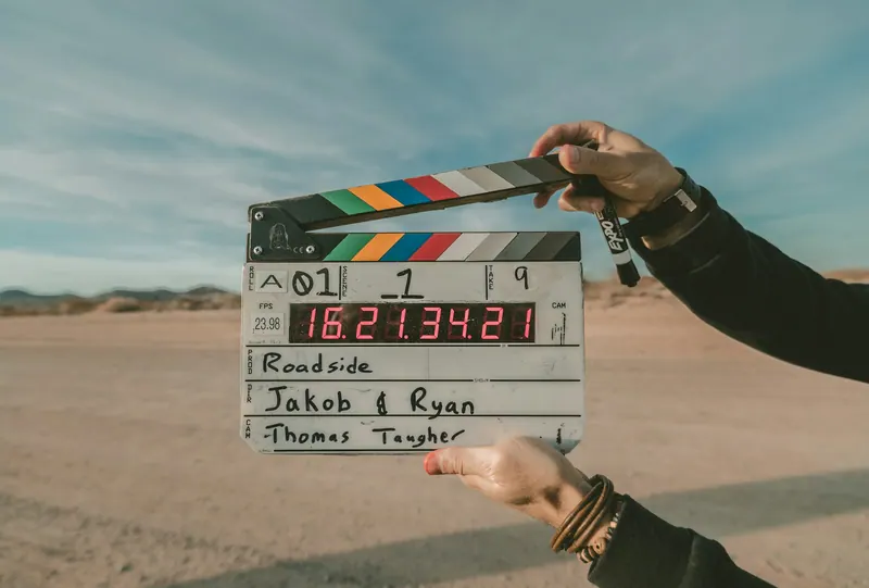 Hands holding a film clapperboard in the desert, brand film video production