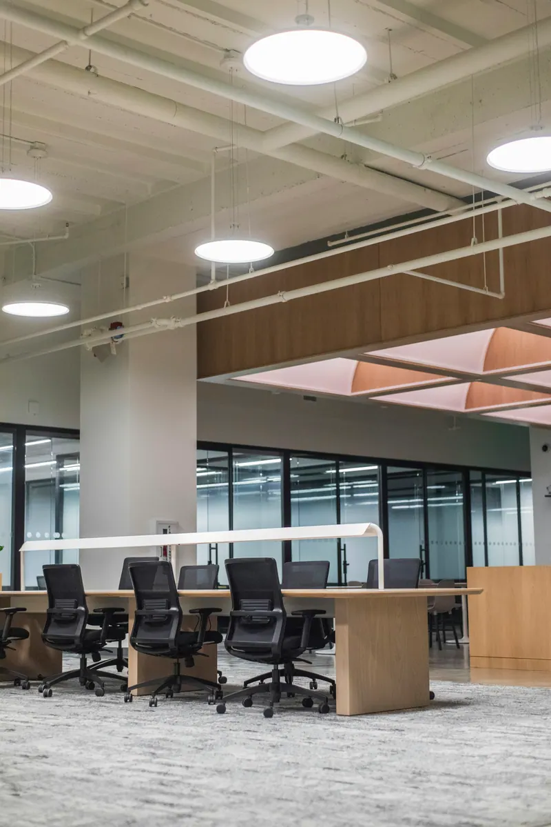 Empty open plan office with desks and ceiling downlights, commercial interior photography
