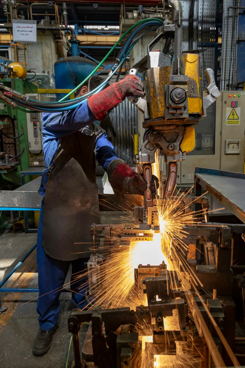 Welder surrounded by sparks on a factory floor, industrial video production
