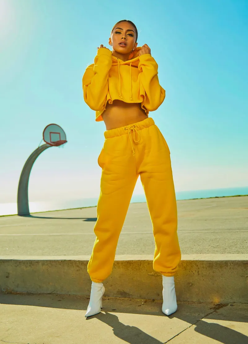Woman in a yellow tracksuit posing on a sunlit street, street fashion photography
