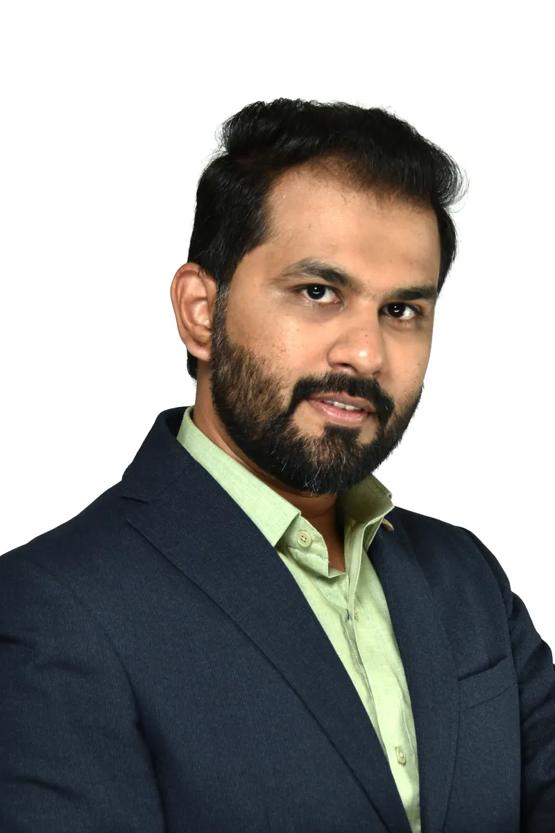 Bearded professional in a navy blazer and light green shirt, business headshot on a white backdrop