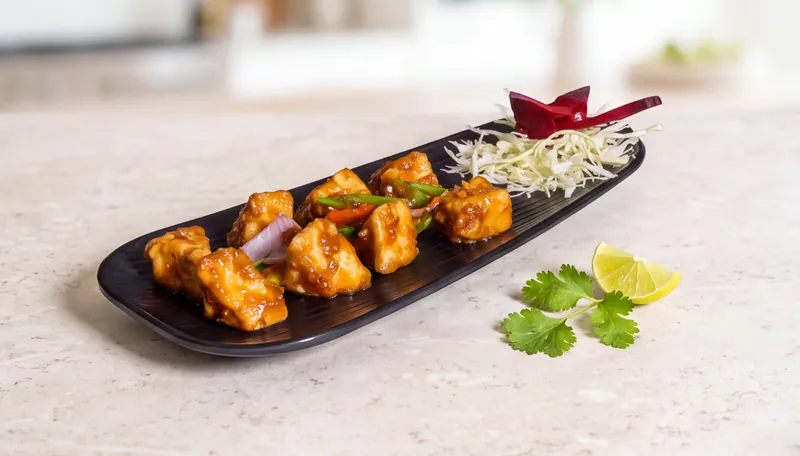 Golden crispy starter bites on a long black platter with onion, cabbage and coriander, restaurant menu food photography in Pune