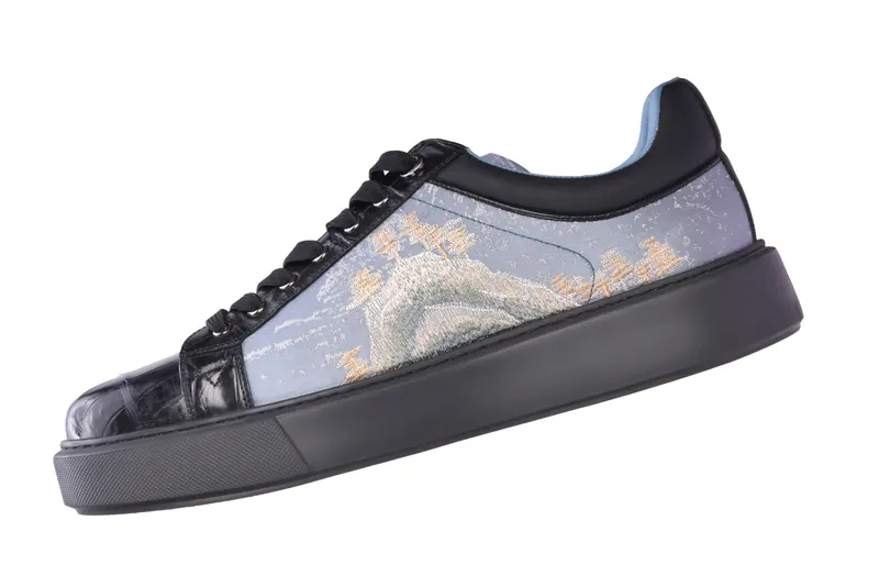 Designer sneaker with a printed fabric side panel and black patent toe cap, footwear product photography in Pune
