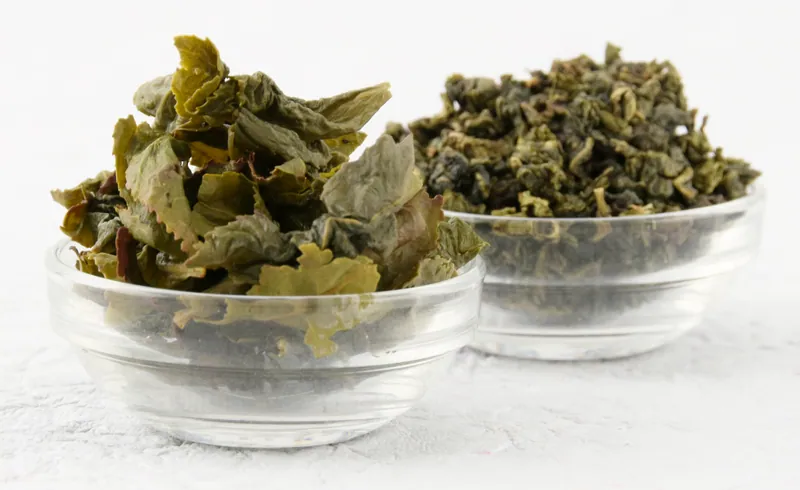 Two glass bowls of dried green tea leaves on a white background, food and beverage product photography in Pune