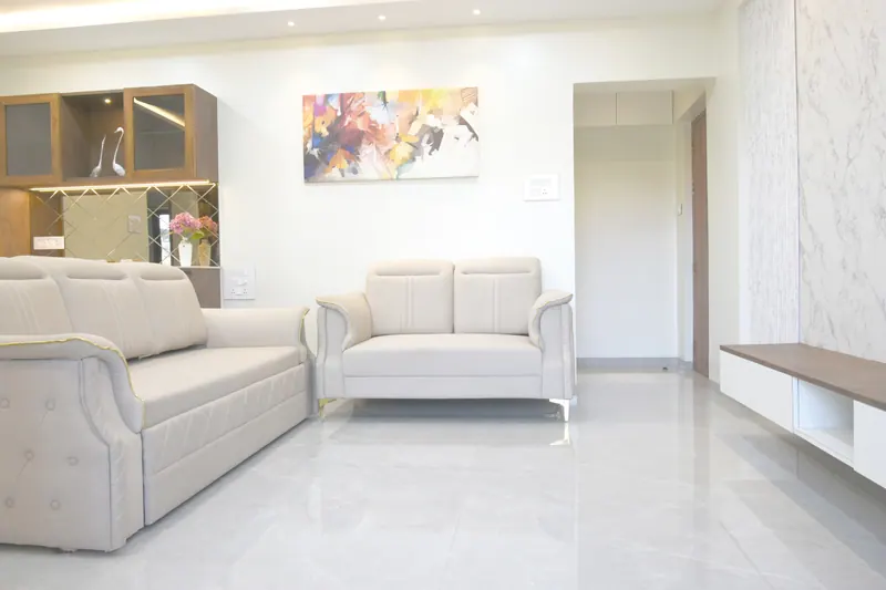 Bright apartment living room with cream sofas, marble feature wall and glossy floor, interior photography in Pune