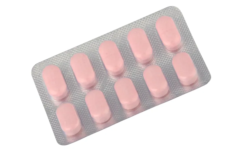Strip of ten pink tablets in a clear blister pack photographed on white, pharmaceutical product photography