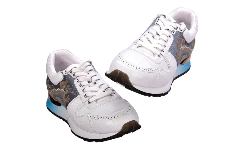 Pair of white leather sneakers with printed panels and a blue gradient sole on white, footwear catalogue photography