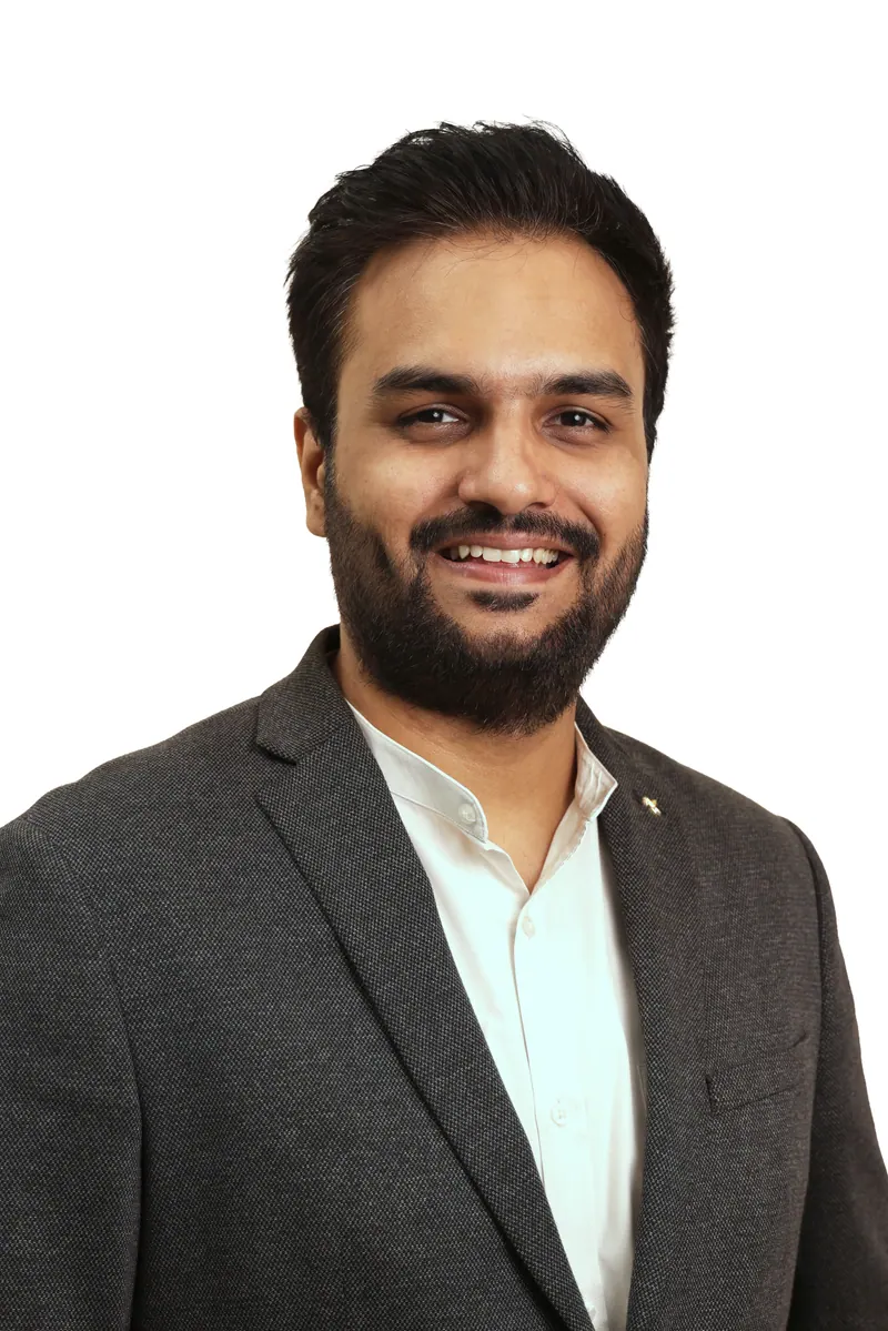 Young entrepreneur in a grey blazer and open collar white shirt, business headshot for a founder profile