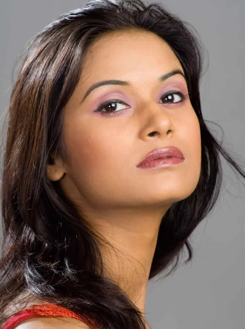 Close beauty portrait of a young woman with soft pastel eye makeup against a grey backdrop